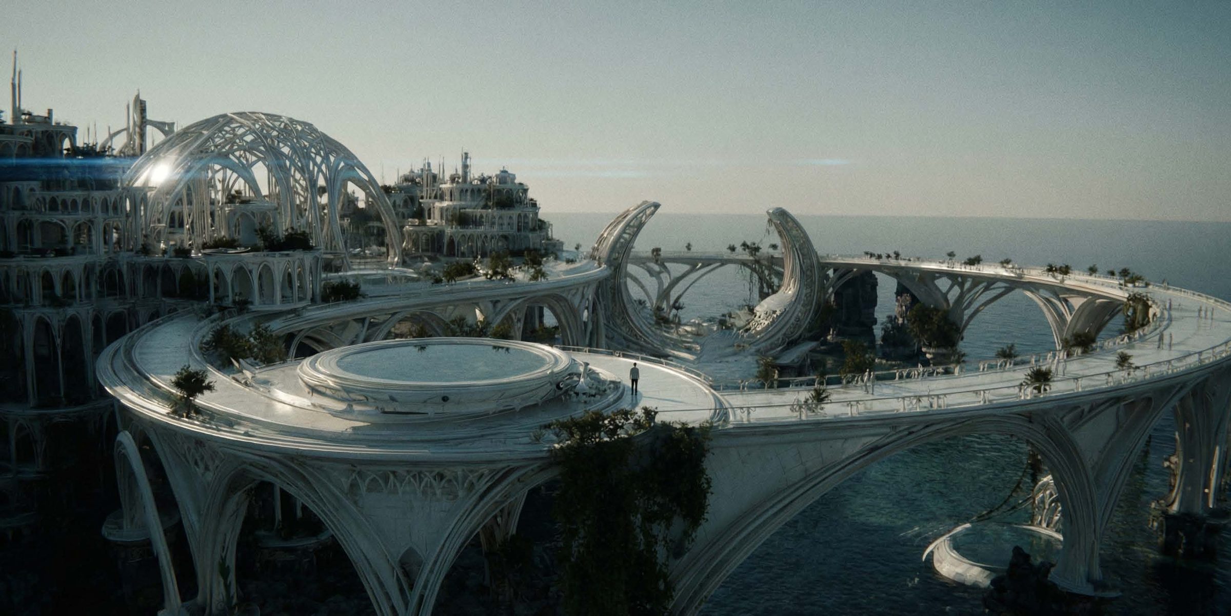 Aerial view of a vast white ceramic-like city built out over a calm ocean under a pale, hazy, cool blue-grey sky: a large ribbed lattice dome of pointed arches and tiered, spired buildings on the left, sweeping curved ca